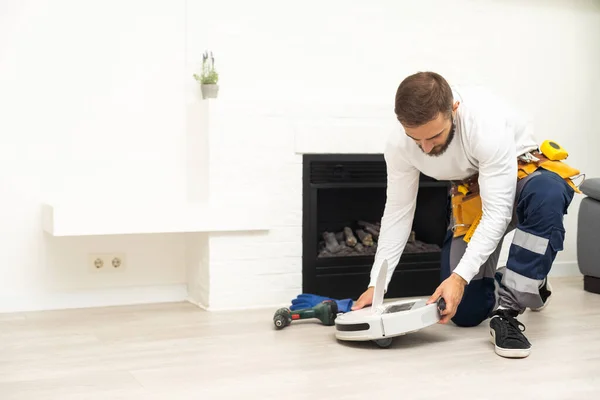 Robot vacuum cleaner repair. Man fixing robot vacuum cleaner DIY at home on the floor. Robotic vacuum cleaner maintenance and service. Smart device for easy housework. New tech for households
