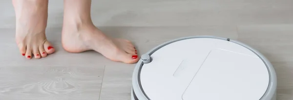 家庭でロボット掃除機を使う女性ロボット掃除機の近くの女性の足 — ストック写真