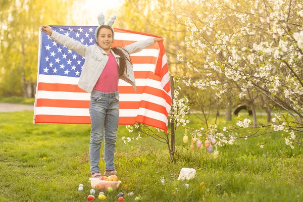 复活节的时候 一个少女在一个盛开的花园里打着美国国旗 — 图库照片