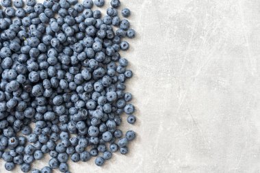 Gri arka planda çiğ organik yaban mersini. Boşluğu kopyala