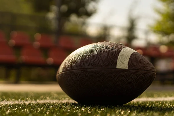American football ball on the grass of a stadium.