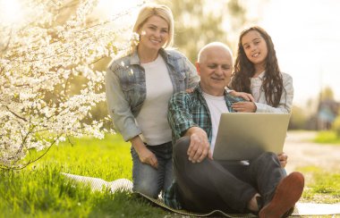 Farklı nesiller mutlu, sevgi dolu aile içeride eğleniyor, dizüstü bilgisayara bakıyor, komik komedi filmleri seyrediyor ya da elektronik cihazda tatil fotoğrafları olan anıları hatırlıyor..