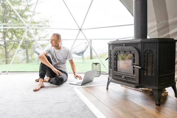 stock image a man works on a laptop in a dome tent.