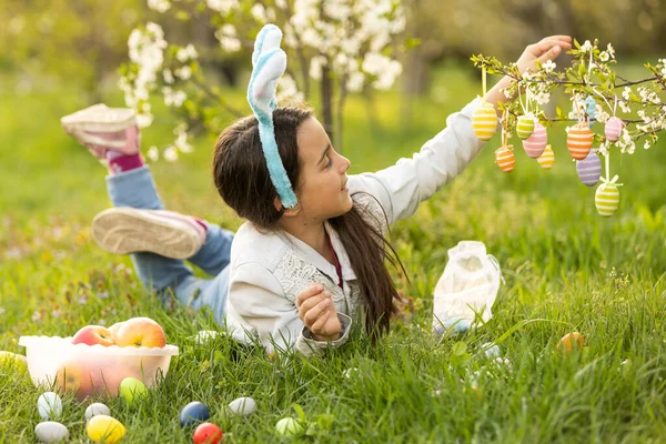 春の日に屋外でカラフルなイースターエッグとウサギの耳を着ている女の子 — ストック写真