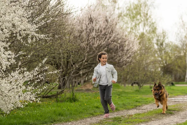 little girl running with a dog in a flower garden.