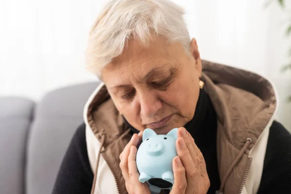Money management concept. Senior elderly woman is holding a piggy bank.