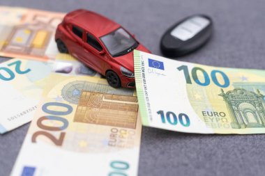 Kırmızı oyuncak araba, 100 Euro 'luk banknotlar, alarm zilli araba anahtarları. Araba kirala, araba al.