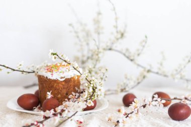 Paskalya pastası ve boyalı yumurta. Çiçek açan buket masanın yanında yatıyor.