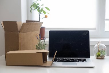 Başlangıç noktasında dizüstü bilgisayar, küçük işletme sahibi, uluslararası paket teslimat konsepti, küresel alımlar ulaşım işi, karton kutular yığını, çevrimiçi satış, e-ticaret