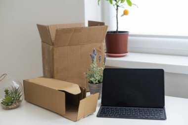 Başlangıç noktasında dizüstü bilgisayar, küçük işletme sahibi, uluslararası paket teslimat konsepti, küresel alımlar ulaşım işi, karton kutular yığını, çevrimiçi satış, e-ticaret