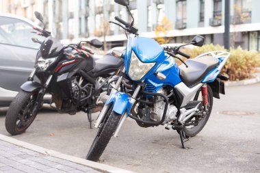 Sokakta arka arkaya park etmiş motosikletli scooterlar.