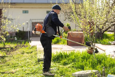 Çimleri biçen adam, çim biçme makinesi yakın.