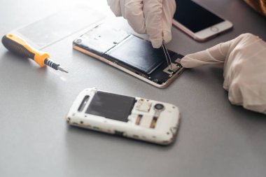 Teknisyen, cep telefonunun içinde lehim kullanarak tamir ediyor. veri kavramı, donanım, teknoloji