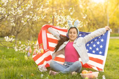 Tavşan kulaklı, renkli yumurta ve Amerikan bayrağı taşıyan bir kız. Paskalya.