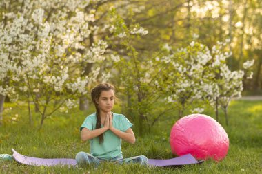 Güzel kız yoga egzersizleri yapıyor, küçük kız bahçede yoga egzersizleri yapıyor.
