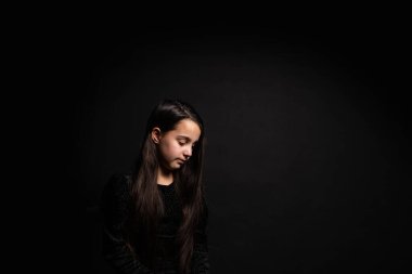 Bir çocuğun portresi. Siyah arka planda küçük bir kız..