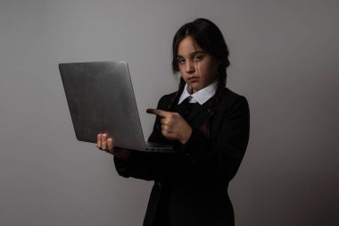 A girl with braids in a gothic style on a dark background with laptop. clipart