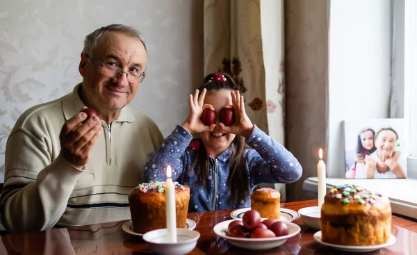 happy grandfather and granddaughter hold easter eggs in hand, folk game beats easter egg.