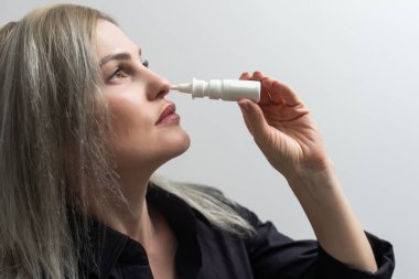 Burnu akan bir kadın elinde ilaç tutuyor.