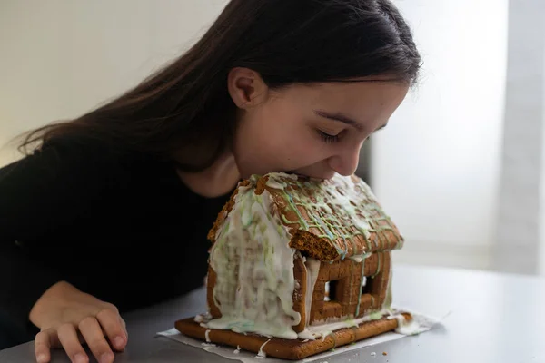 Kids with gingerbread house, A teenage girl is eating a gingerbread house.