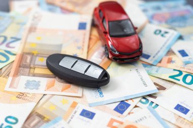 Paranın arka planında oyuncak bir araba ve araba anahtarları..