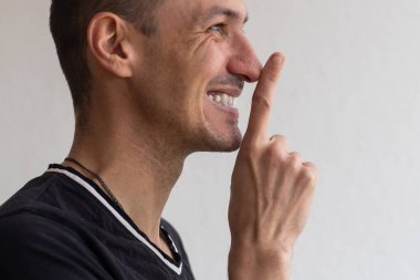 Dudaklarının yanında sakal tutan, sırlarını saklayan, sürpriz hazırlayan olumlu gülümseyen bir adam. Beyaz arka planda izole edilmiş kapalı stüdyo görüntüleri