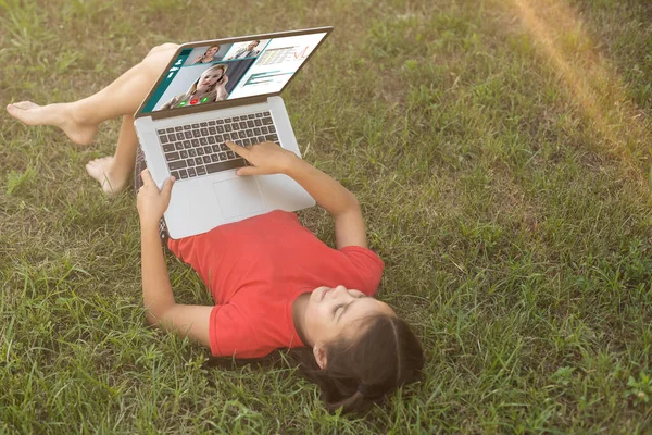 little girl learns, a teenager working on laptop lying on a meadow. mobile Internet in rural areas. distance education.
