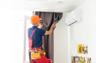 man doing house works, attach the railing and hang curtains at home