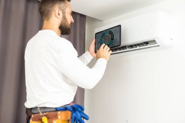 male technician service worker diagnosing for repairs air conditioner. person using tablet