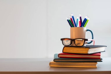 Bir yığın kitap ve kalemli bir kupa..