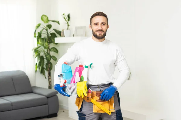 Young male worker of cleaning service with supplies on white background.