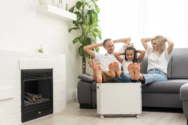 Family warming up near home heater at winter cold time. The symbolic image of the heating season at home