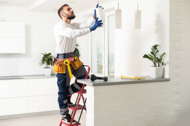 Electrician mounting ceiling lamp - installing the wires