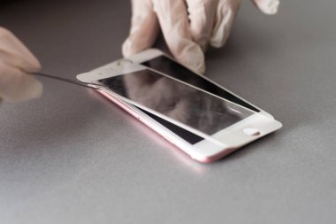 Akıllı çözüm teknolojisi konsepti. Koruyucu filmin yerine yenisini koymuşlar. Adam dikkatle akıllı telefon ekranından eski koruyucu camları kaldırıyor.