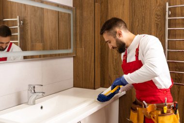 Profesyonel tesisatçı, üniformalı erkek işçi yeni daireye lavabo ve su borusu kuruyor..