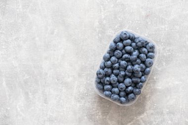 Beyaz arka planda paketlenmiş plastik bir kutuda taze yabanmersini. Metin için boşluk