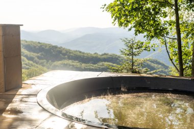 Sıcak su ve banyo, spa ve rahatlama için bitkilerle dolu büyük bir fıçı. dağlar.