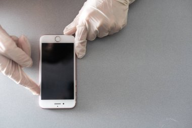 Elinde mavi koruyucu eldivenle beyaz arka planda izole edilmiş boş bir akıllı telefon. Bir metin için boşluk kopyala