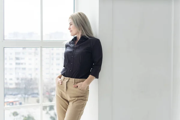Young business woman wearing suite standing near window