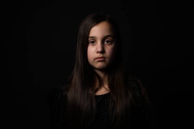 Siyah arka plan üzerinde üzgün küçük kız portresi.