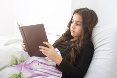 pre teen girl writing diary in bedroom.