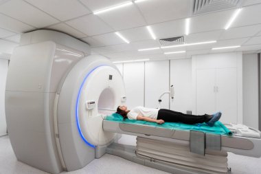 Modern hastane laboratuvarında tıbbi tomografi ya da MRI taraması. Radyografi bölümünün içi. Beyaz odada teknolojik olarak gelişmiş ekipmanlar var. Manyetik rezonans tanılama makinesi.