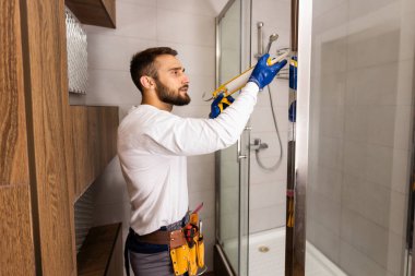 Tesisatçı banyoya duş kabini kuruyor..