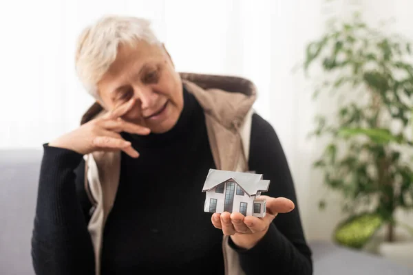Happy realtor woman holding tiny house model on hand, palm, showing object at camera, promoting agency service, help with house, property buying apartment rent, mortgage
