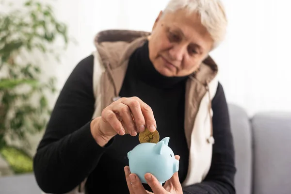 Money management concept. Senior elderly woman is holding a piggy bank.