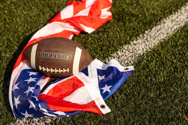 American football on green grass, on flag of United States of America background