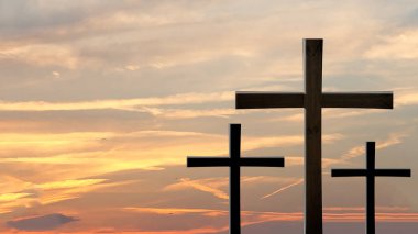 Bulutlu gökyüzünün altındaki bir yamaçta üç haç dik duruyor. Yüksek kalite fotoğraf