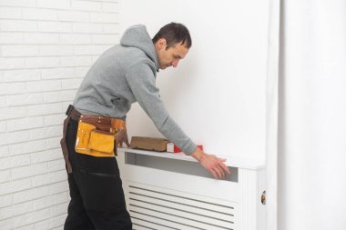 repairman using tools while installing or repairing heating radiator. plumber installing heating system in apartment. radiator installation, plumbing works and home renovation.