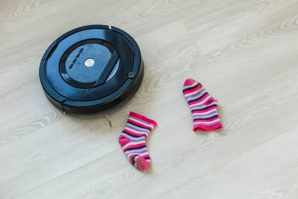 The robot vacuum cleaner drives on the laminate floor. Smart House. Home assistant concept