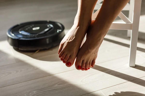 The robot vacuum cleaner drives on the laminate floor. Smart House. Home assistant concept
